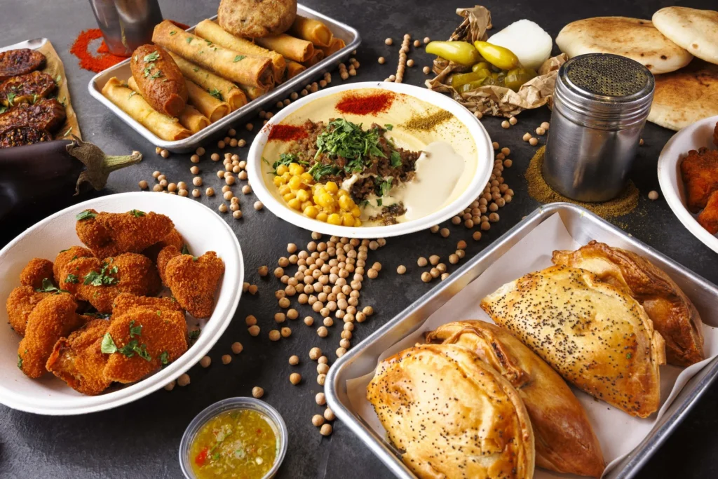 מגוון מנות על השולחן: חומוס, עוף פריך ומאפים ממולאים